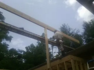 Carpenter setting a ridge beam over a new addition frame — Ice Dam Removal by Roofing Brothers in Cloverdale