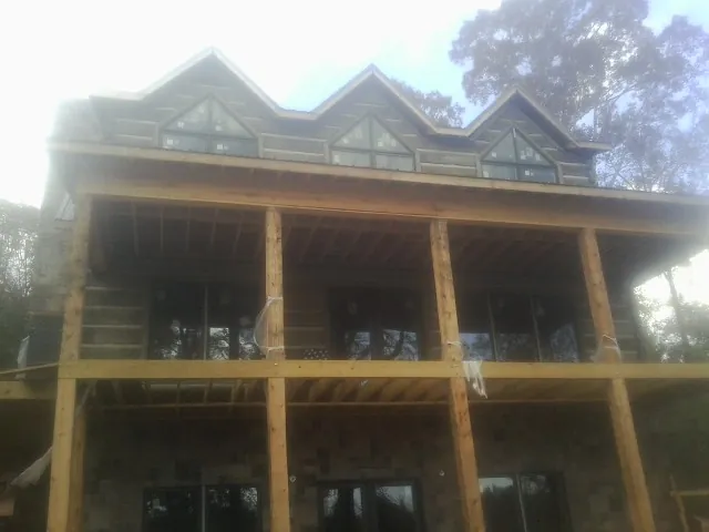 Dormers and porch framing on a large log home under construction — Roof Coating work by our crew in Cloverdale